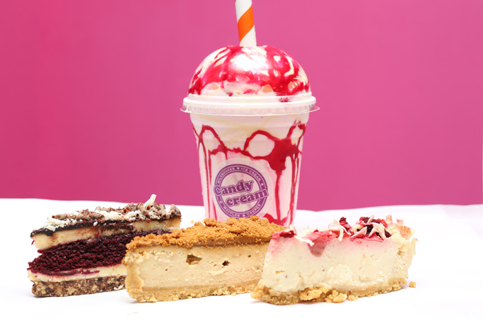 Gourmet Candy Cream milkshake topped with red syrup, surrounded by slices of red 
velvet cake and cheesecake at the Bathgate dessert shop 