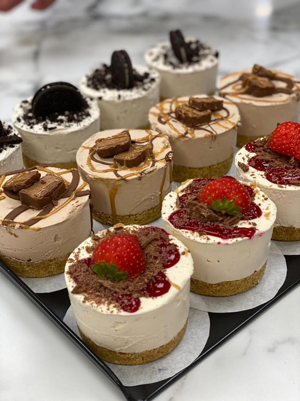 Mini cheesecakes on a tray with popular toppings, including fresh strawberry and 
chocolate shavings, Oreo, and chocolate bars, from Candy Cream Bathgate 